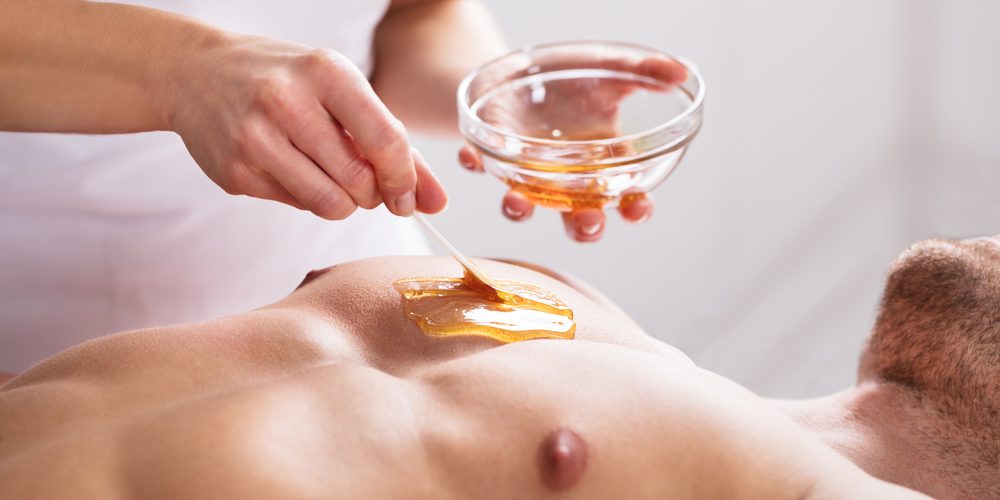 Close-up Of A Therapist Applying Wax On Man's Body